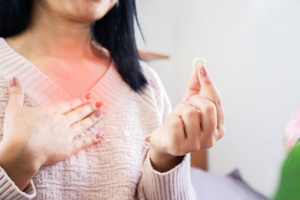 woman hand taking medicine for GERD, having problem with heartburn from acid reflux disease stock photo