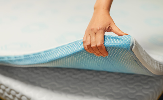 Woman hand testing orthopedic memory foam mattress topper.