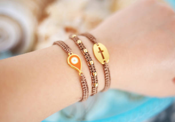 woman hand wearing stylish brown bracelets with evil eye and cross - macrame bracelets stock photo
