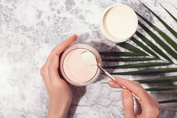 Woman hands, collagen powder and smoothie. Woman pour collagen powder or protein in morning smoothie or yogurt. Natural beauty and health supplement. Healthy lifestyle. Flatlay, top view. Copy space. collagen stock pictures, royalty-free photos & images
