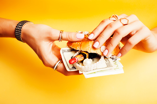 woman hands holding hamburger with money, jewelry, cosmetic, social issue wealth concept close up