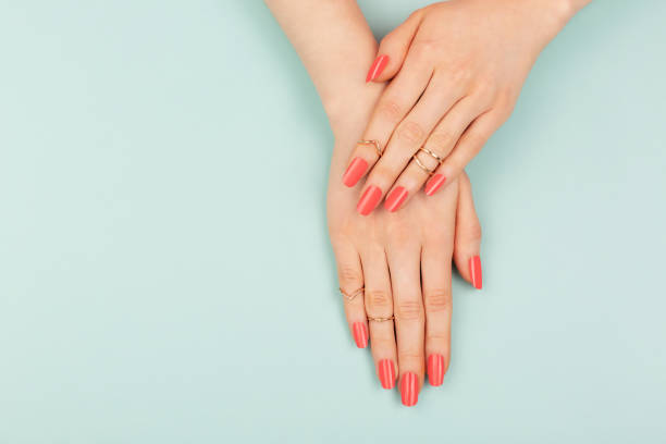 Woman hands on blue background Manicure in trendy coral color. Woman hands on blue background. Color of 2019 year concept. Summer vibes. Copy space for your text. lacquered stock pictures, royalty-free photos & images