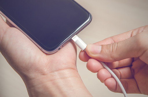 Woman hands plugging a charger in a smart phone