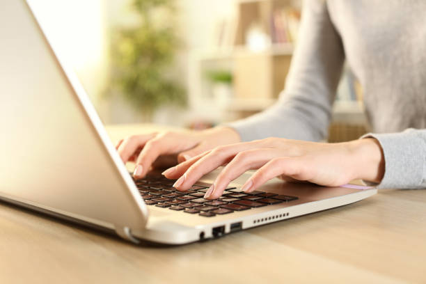 Woman hands typing on laptop sitting at home Close up of woman hands typing on laptop sitting on a desk at home hot desking stock pictures, royalty-free photos & images