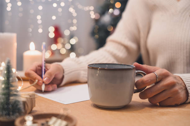 Woman hands with pen and cup writing christmas wish list, goals.