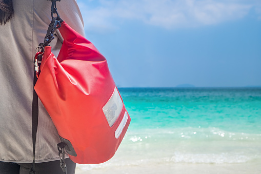 Woman Hang Dry Pack(Waterproof Luggage) on the Beach and Looking at Tropical Blue Ocean, Thailand