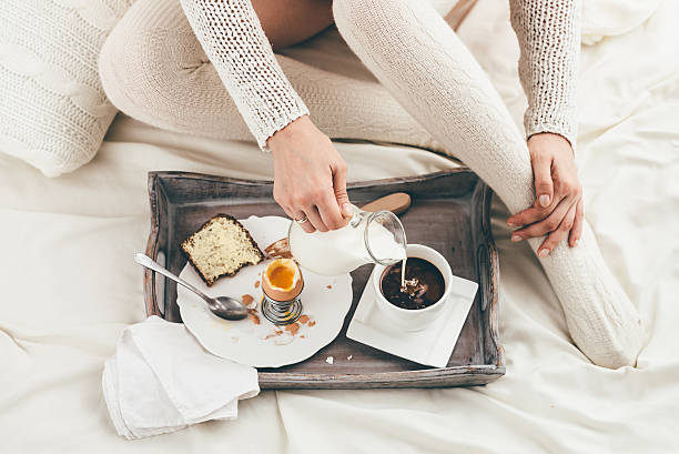 Woman having breakfast in bed. Window light stock photo