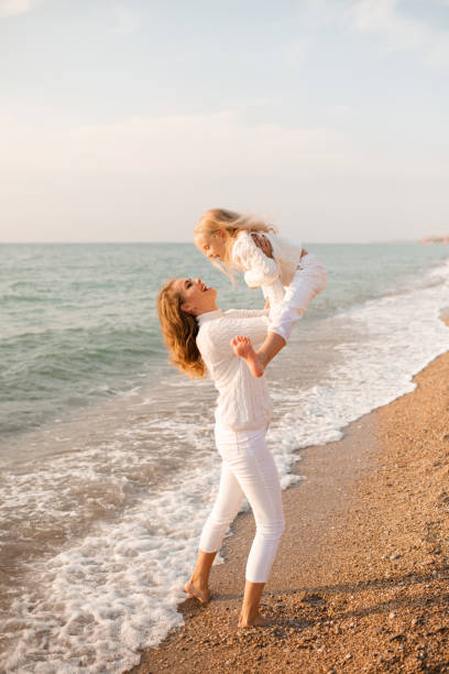 Woman having fun with child daughter at beach stock photo