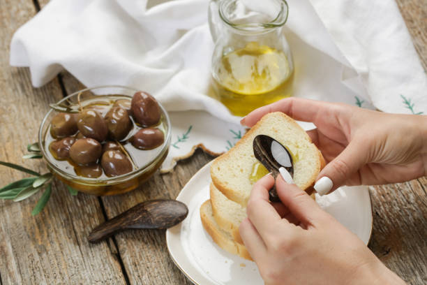 woman having healthy snack, olives, olive oil and bread. - cold-pressed olive oil 個照片及圖片檔