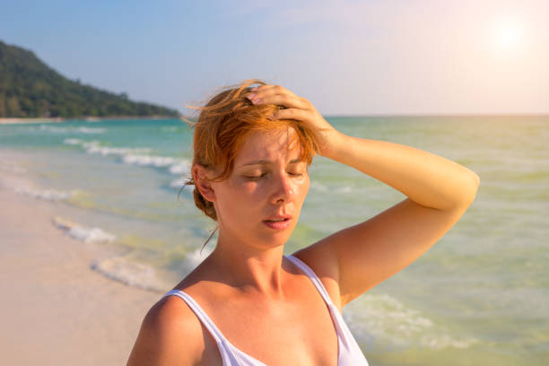 Woman having sun stroke on sunny beach. Woman on hot beach with sunstroke. stock photo