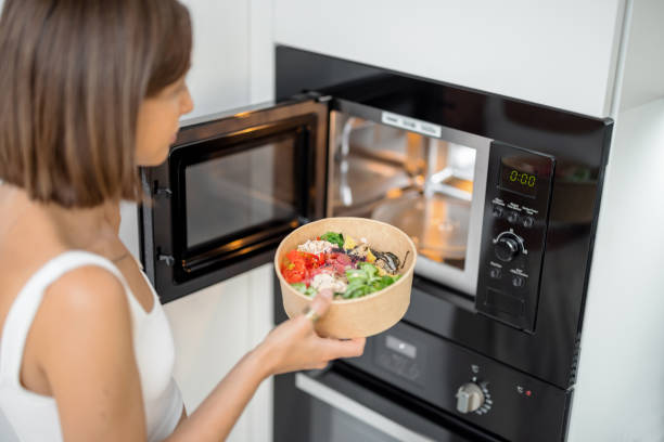 Woman heating food with microwave machine stock photo