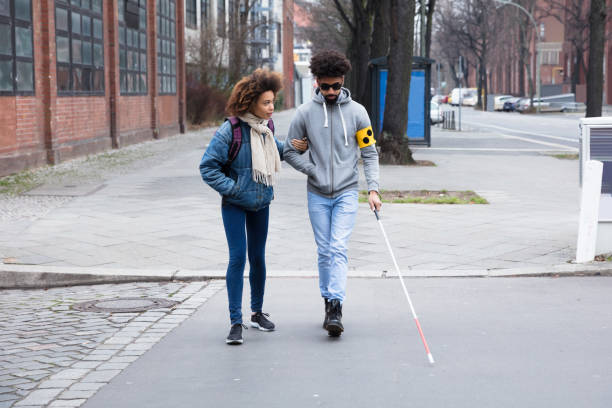 mujer ayudando a ciego al cruzar carretera - ceguera fotografías e imágenes de stock