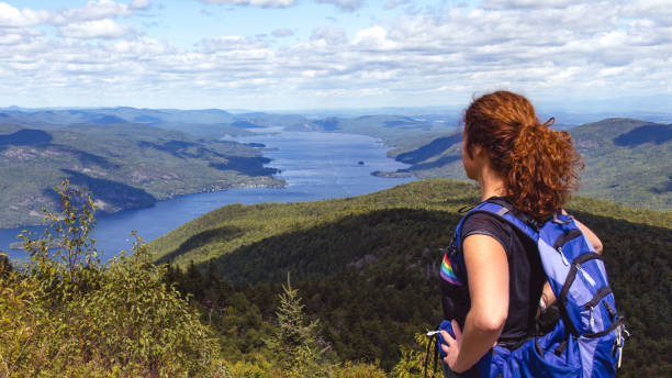 Woman Hiker Enjoying view from Black Mountain Summit overlooking Lake George, Adirondacks, New York stock photo