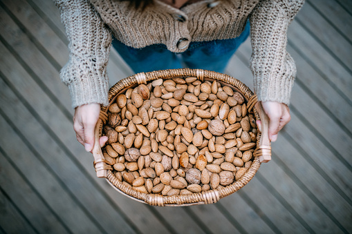 Woman Holding a Basket of Almonds and Walnuts