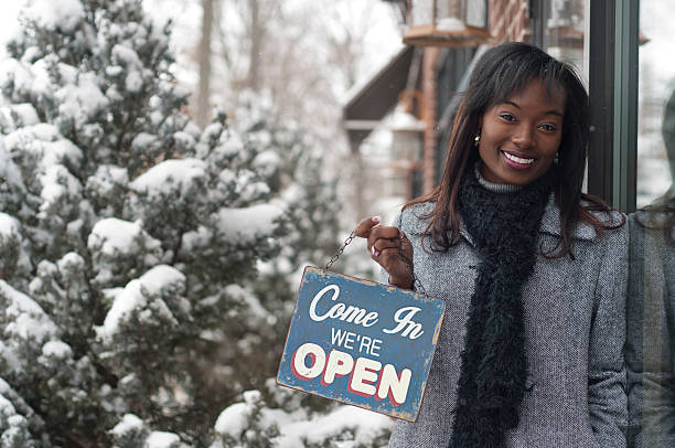 Woman holding a Come In We're Open sign stock photo