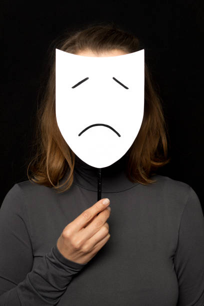 Woman holding a face mask with sad emotion. Depression concept. stock photo