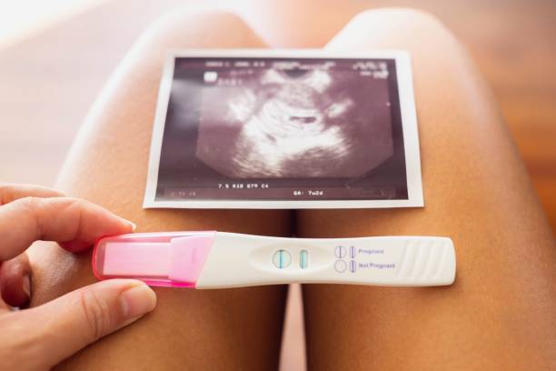 A woman holding a pregnancy test and a photo of the baby. Planning to be a mother. A mother to be coming back from the doctor holding a pregnancy stick and a photo of a new little baby. Happy mom. positive pregnancy test stock pictures, royalty-free photos & images