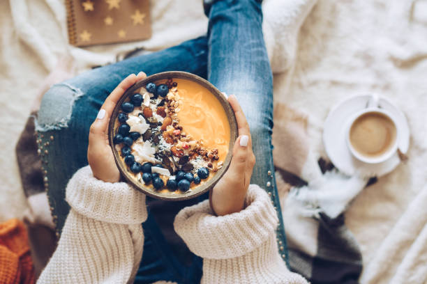 Woman holding a pumpkin smoothie bowl Pumpkin pie smoothie bowl topped with berries, granola, and coconut flakes hygge stock pictures, royalty-free photos & images