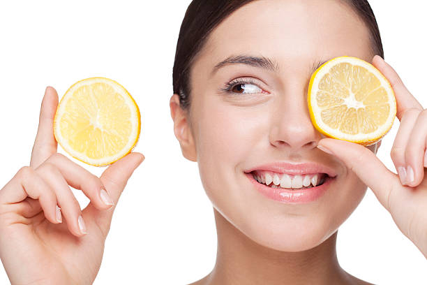 A woman holding a slice of lemon over her eye stock photo
