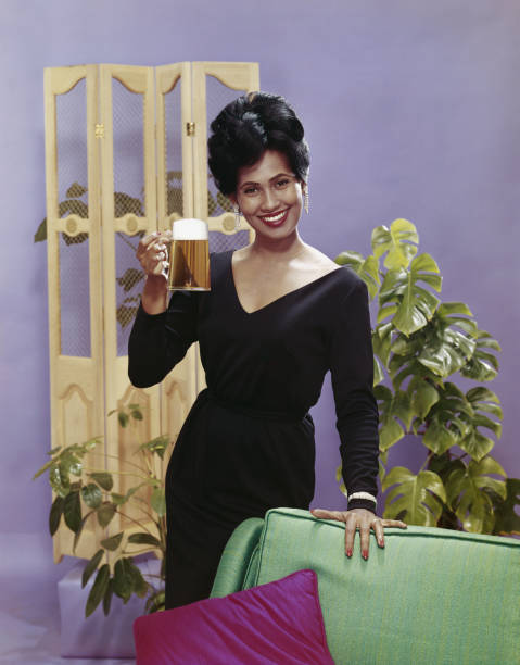 Woman holding beer glass beside sofa, smiling, portrait  1964 stock pictures, royalty-free photos & images
