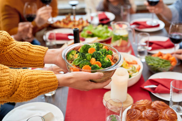 donna che tiene ciotola verdure piene sopra servito tavolo da pranzo - cena natale foto e immagini stock