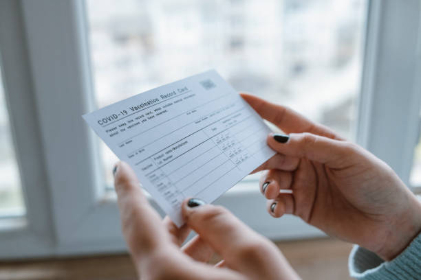 Woman holding COVID-19 Vaccination Record Card. Close up of cropped female hands holding COVID-19 vaccination record card. cdc vaccine card stock pictures, royalty-free photos & images