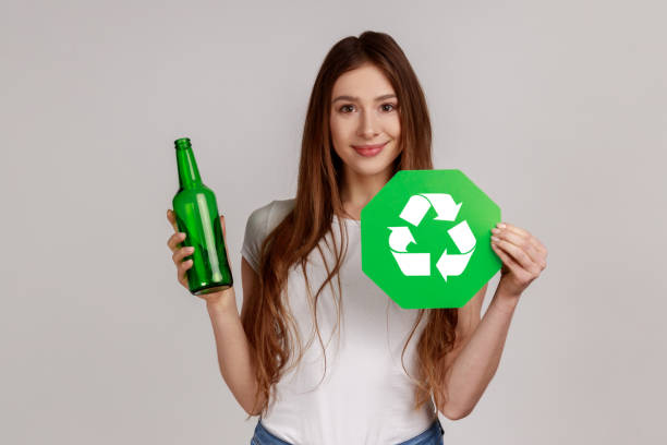 Woman holding glass bottle and green recycling sign, garbage sorting and environment protection. stock photo