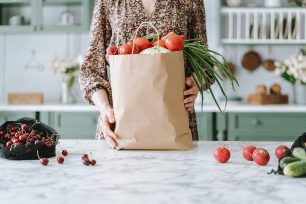 woman holding paper grocery bag with vegetables - paper bag craft imagens e fotografias de stock