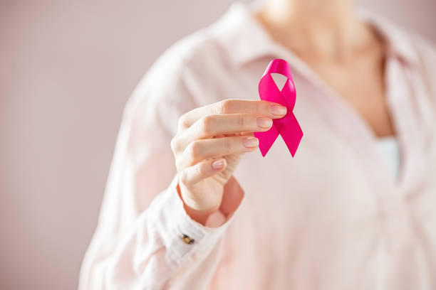 Woman holding pink breast cancer ribbon stock photo