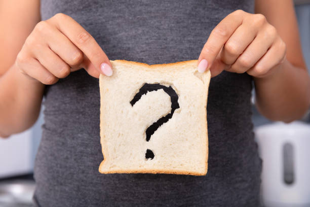 Woman Holding Slice Of Bread With Question Mark Sign Mid-section Of A Woman Hands Holding Sliced Bread With Question Mark Sign dough stock pictures, royalty-free photos & images