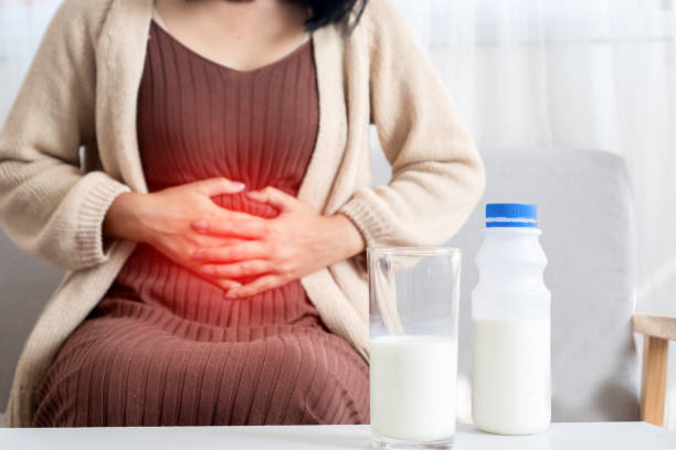 woman holding stomachache after drinking a glass of cow milk feeling bad, discomfort because of expired date, indigestion concept stock photo