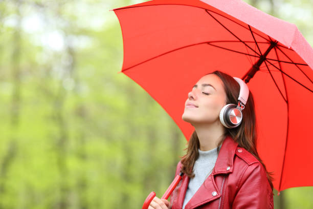 femme tenant un parapluie écoutant de la musique dans un parc - telecharger image gratuit photos et images de collection