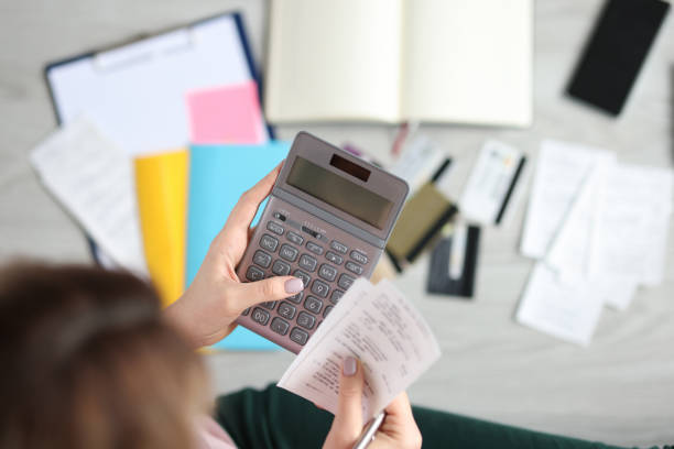 Woman holds calculator and paid check closeup stock photo