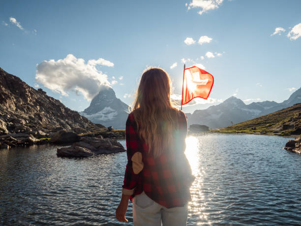 Woman holds Swiss flag against mountain landscape, Zermatt stock photo