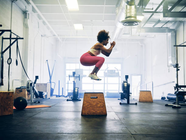 Woman in a Cross Training Gym A woman working out alone in a cross training gym. cross training stock pictures, royalty-free photos & images