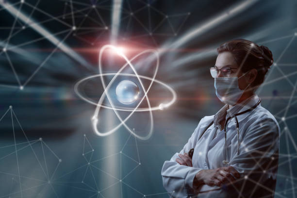A woman in a mask in uniform looks at an atom on a blurred background. stock photo