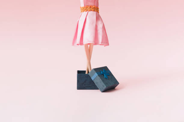 een vrouw in een roze kleding komt uit een blauwe giftdoos. roze achtergrond. - barbie stockfoto's en -beelden