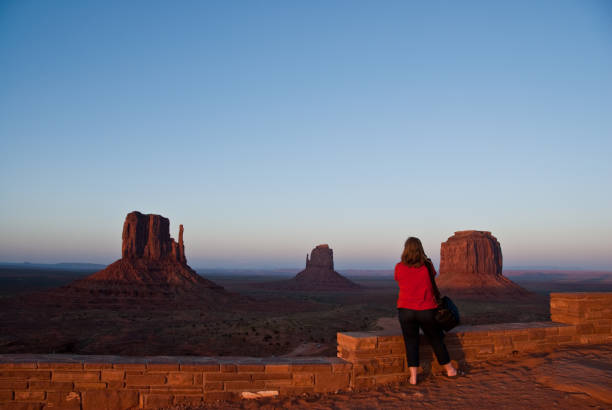 Woman in a Red Blouse Monument Valley Tribal Park, Arizona, USA - May 14, 2012: A woman in a red blouse is taking a picture of Monument Valley near Kayenta, Arizona. The view of the Mittens and Merrick Butte at sunset was from the visitor center. jeff goulden monument valley stock pictures, royalty-free photos & images