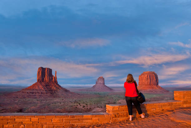 Woman Taking a Picture of Monument Valley Monument Valley Tribal Park, Arizona, USA - May 14, 2012: A woman in a red blouse is taking a picture of Monument Valley near Kayenta, Arizona. The view of the Mittens and Merrick Butte at sunset was from the visitor center. jeff goulden monument valley stock pictures, royalty-free photos & images