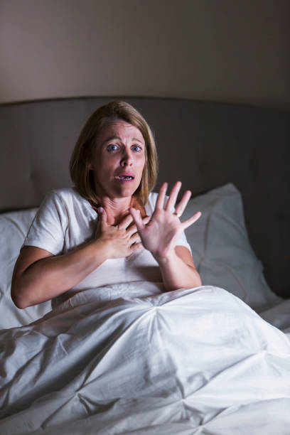 kvinna i sängen vaknat av något hemskt - medelålders kvinna bröstsmärtor bildbanksfoton och bilder
