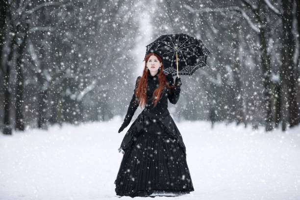 Woman in black Victorian dress in the winter park stock photo