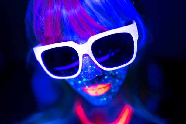 Woman in blue neon paint and fluorescent sunglasses Woman in blue neon paint and fluorescent sunglasses. Woman painted with fluorescent make up. paint neon color neon light ultraviolet light stock pictures, royalty-free photos & images