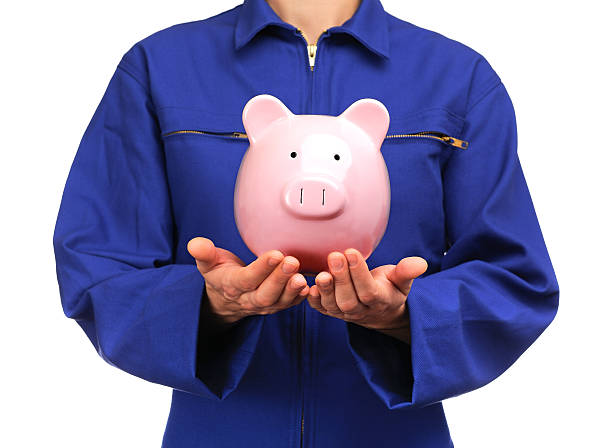 woman in blue work uniform holding a piggy bank stock photo
