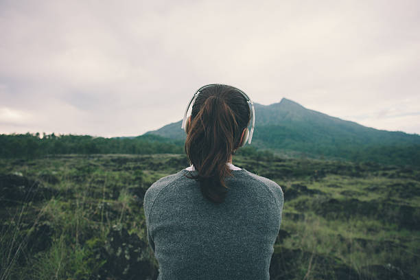 Woman in headphones listening music in nature stock photo