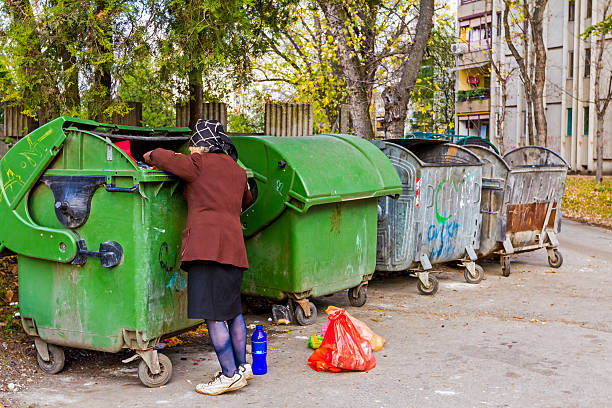 Woman in poverty Homeless woman is searching for food in garbage dumpster. Woman in poverty is searching something in container. scavenging stock pictures, royalty-free photos & images
