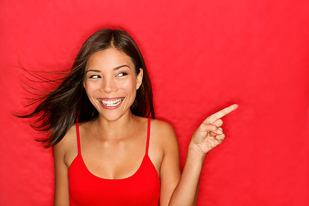 Woman in red laying in a red sheet pointing stock photo