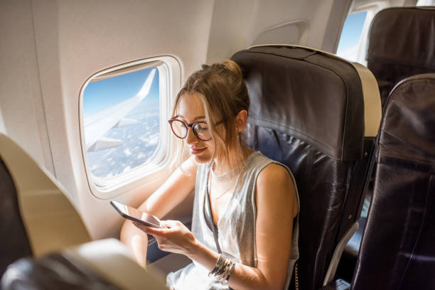 Woman in the airplane Young woman sitting with phone on the aircraft seat near the window during the flight in the airplane passenger stock pictures, royalty-free photos & images