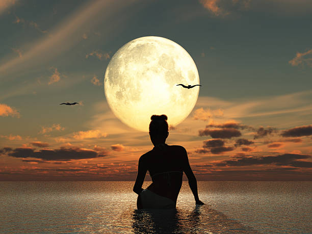 Woman in the sea watching the full moon stock photo