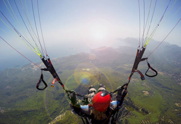 Woman in the sky paragliding Paragliding in the sky. Woman girl is soaring in the sky on paraplane above mountains ans sea paragliding stock pictures, royalty-free photos & images