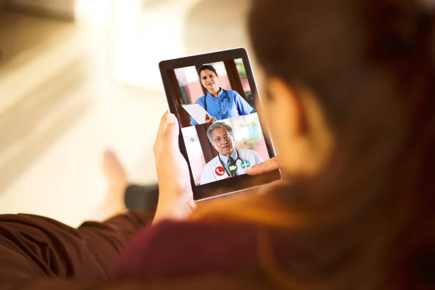 Woman in video conference with doctor Sick woman video conferencing with doctors using digital tablet nurse talking to camera stock pictures, royalty-free photos & images